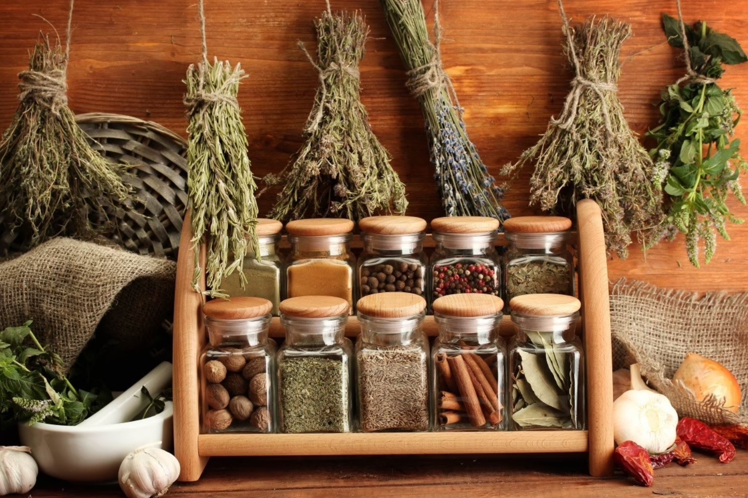 Wooden spice rack with 8 glass jars and dried herb bundles