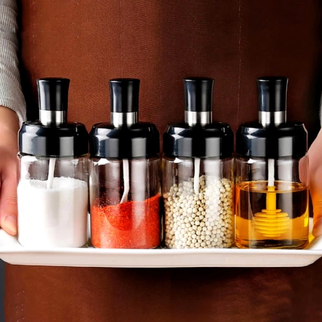 Set of four spice dispenser jars on a white tray